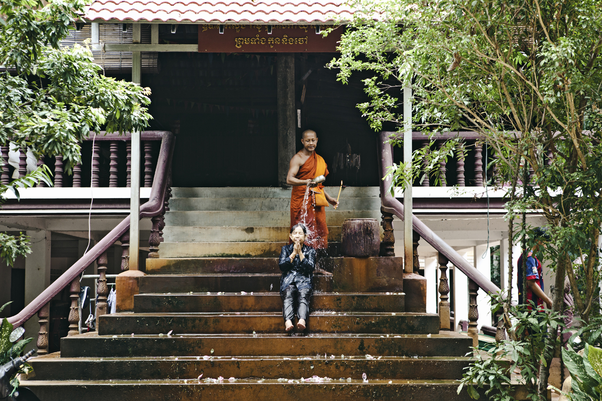 Angkor w jeden dzień. Mnich polewa głowę kobiety wodą. Błogosławieństwo. Kambodża.