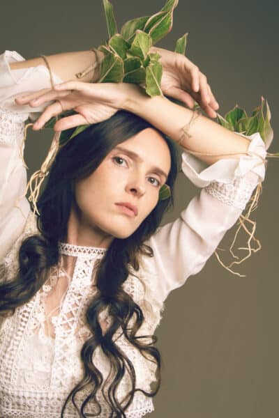 portret kobiety z zielonymi liśćmi owiniętymi wokół dłoni