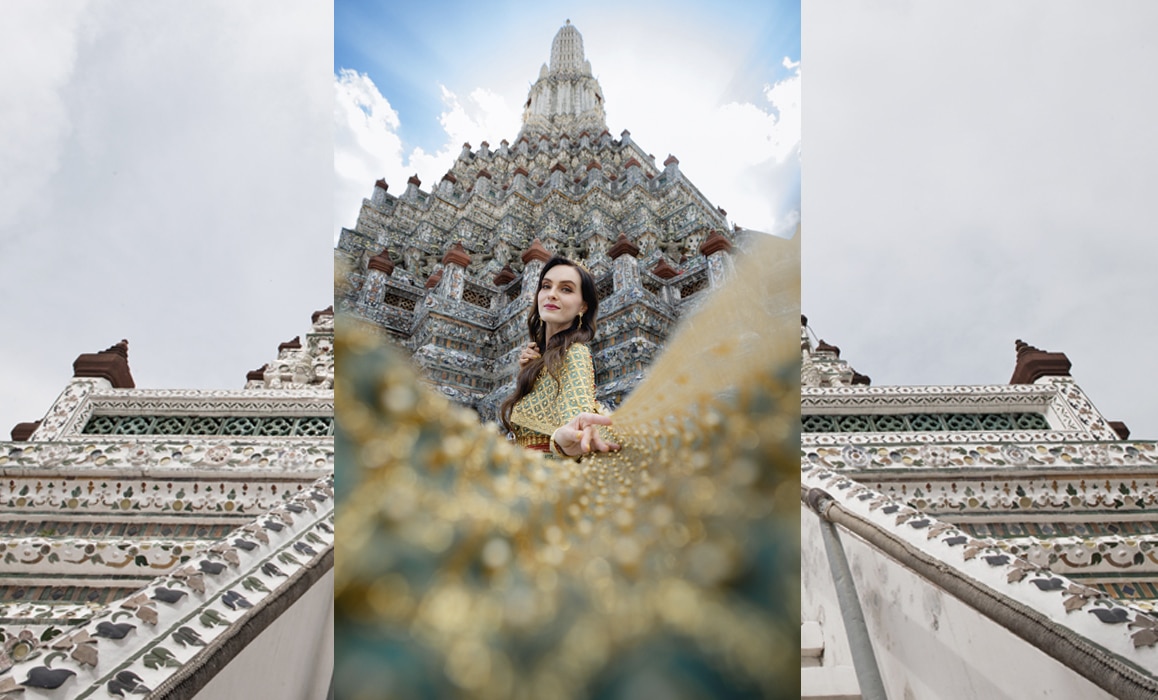 Kobieta w tradycyjnym tajskim stroju na tle Wat Arun w Bangkoku.