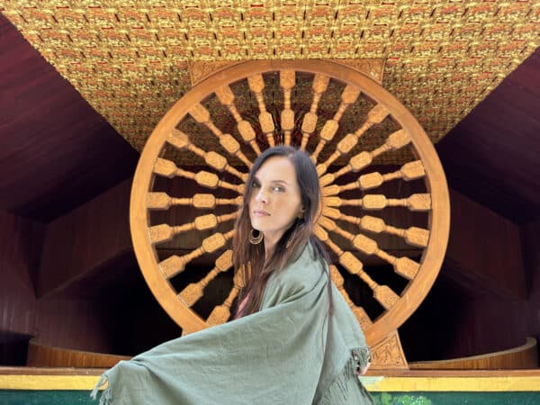 Kobieta na tle drewnianego koła w świątyni Chedi Puttha Khaya w Sangkhlaburi.